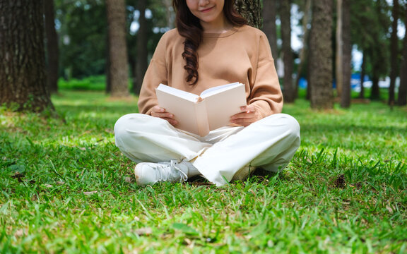 Closeup image of a woman reading a book while sitting in the park