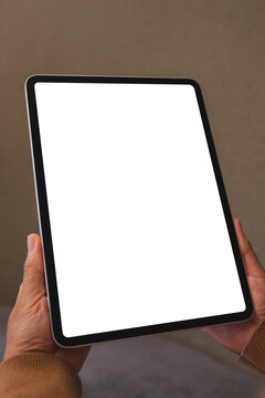 Vertical mockup image of a woman holding digital tablet with blank white desktop screen in cafe