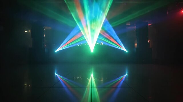 Vibrant colorful laser light show with intricate beams of green blue and red light creating dynamic patterns on stage floor in smoky dark interior nightclub or event venue