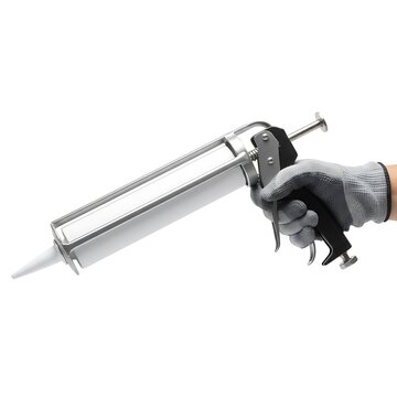 Hand holding a caulking gun in a workshop setting during daylight