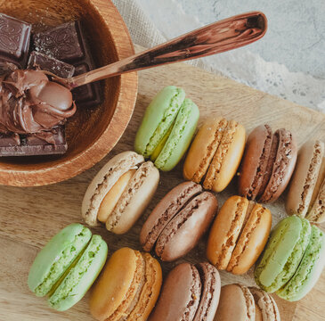 Bunte Macarons mit Schokolade auf Holzbrett. S&uuml;&szlig;es Dessert mit Macarons und Schokolade. S&uuml;&szlig;es Dessert mit Macarons und Schokolade
