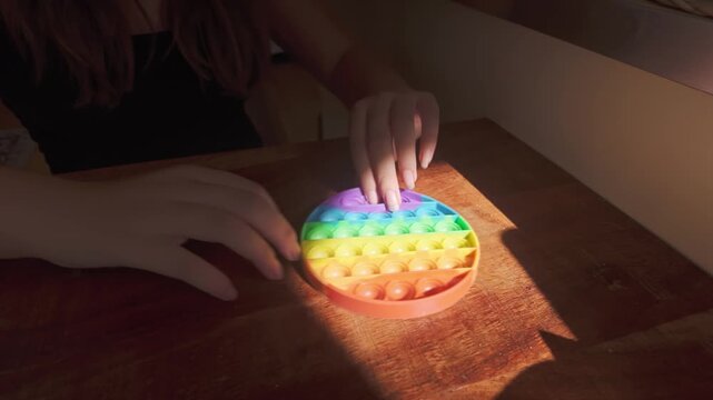 Youth plays with Pop-It and squishy ball toys, demonstrating tactile sensory play as a relaxing pastime and everyday leisure activity.