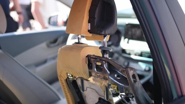 Disassembled car seat exposes metal frame foam padding headrest supports and internal structure during automotive interior repair restoration and maintenance service