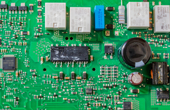Detailed close-up of a green electronic circuit board featuring various microchips, capacitors, and soldered components.