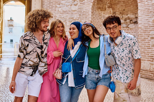Diverse Group Of Young Friends Laughing And Walking Together Through Historic City Streets On Vacation