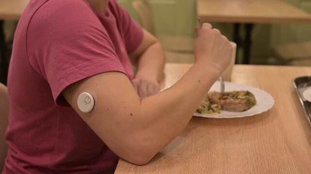 A woman with a continuous glucose monitor is eating in a cafe. 