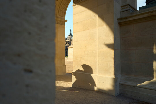 Shadow of a person on a sunlit stone archway in Paris