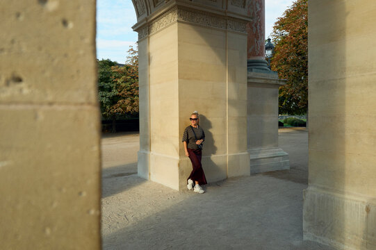 Stylish blonde woman posing by a stone monument on a sunny day