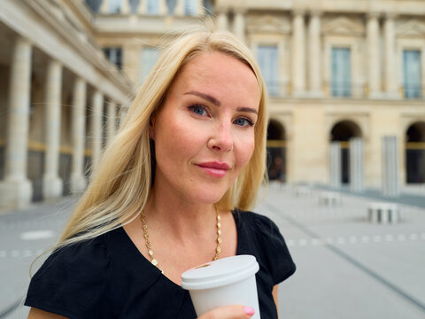 Blonde woman holding a coffee in Paris