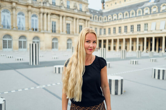 Happy blonde woman visiting the Palais Royal in Paris