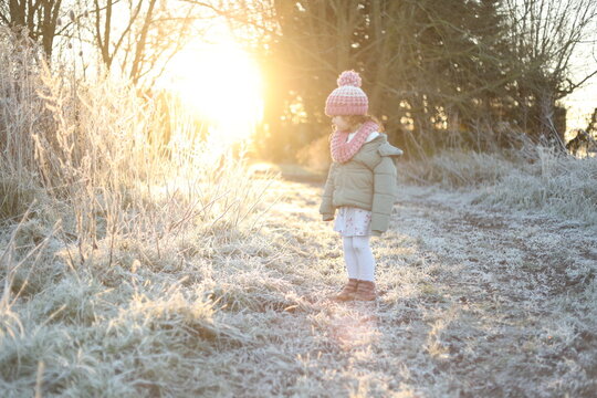 Little girl in a frosty field at sunrise