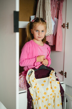 Little girl with pigtails choosing her outfit in the closet