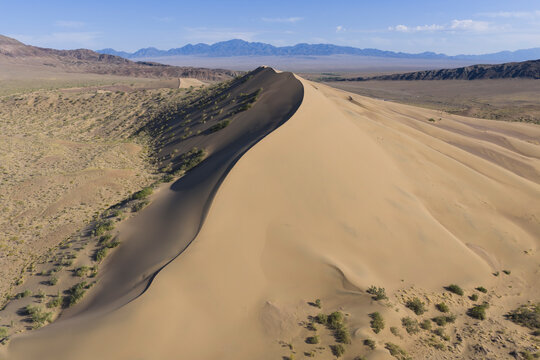 Aerial view of a dramatic sand dune in a vast desert landscape