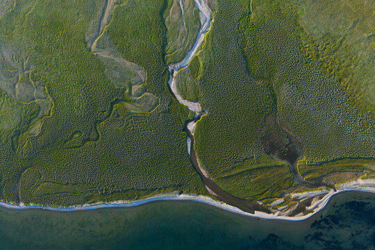Aerial view of a river delta flowing through green marshland