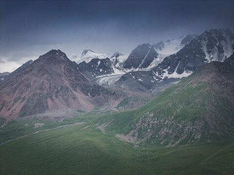 Lush green valley below snow capped mountains