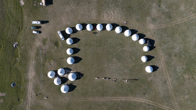 Aerial top down view of a yurt camp in a grassy field