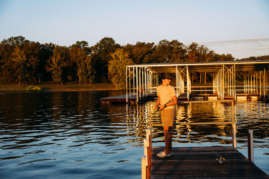 Teenage Boy Fishing Off Dock On Autumn Morning