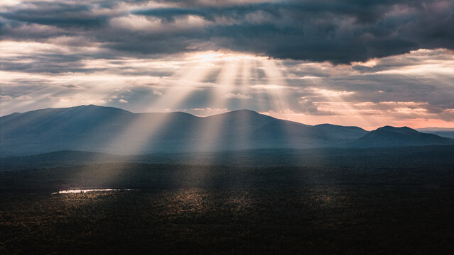 Heavenly sunbeams shine down on a mountain landscape, Maine