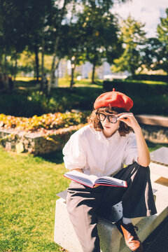 Young woman in a red beret reading on a park bench