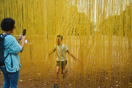 Woman photographing boy inside immersive yellow art installation