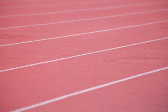 Red running track lanes with white dividing lines close up at sports stadium stadium