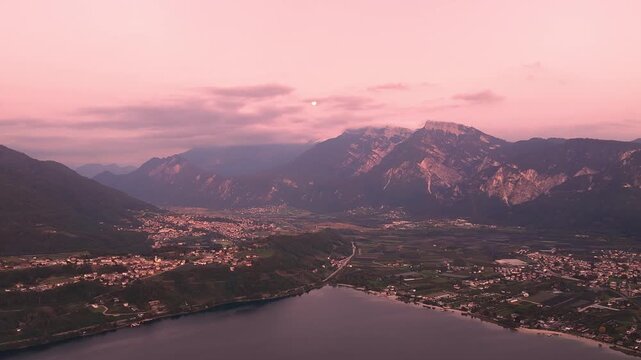 Alpine lake and valley towns beneath rugged mountains glowing