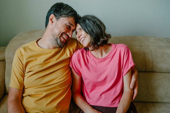 Happy husband and wife share love on the couch indoors