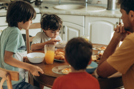 Father and sons eat breakfast at the kitchen table
