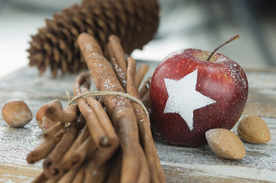 Christmas apple with snow star, cinnamon sticks, fir cones, almonds and hazelnuts on table