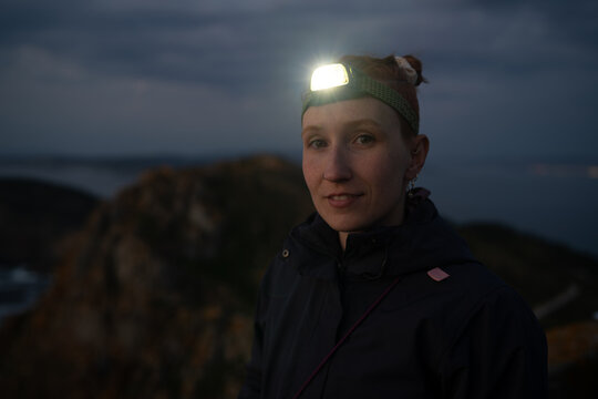 A woman wears a headlamp during a night hike outdoors