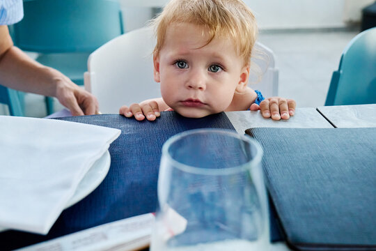 Toddler girl peeks over a restaurant table during a family meal