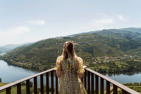 Woman in dress looks at Douro river valley from balcony in Portugal