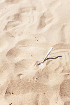 A silver spoon sticks out of the dry desert sand