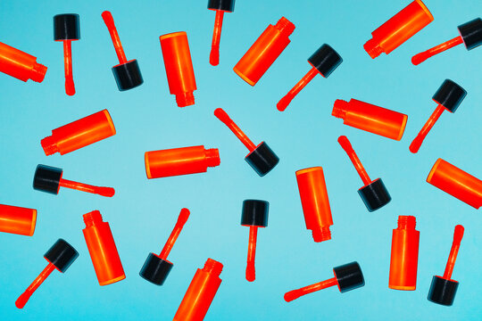 Scattered red lip gloss tubes cover a bright blue background