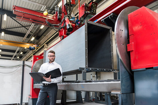 Male engineer holds folder in a modern production facility