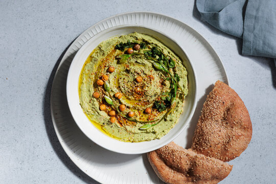 Homemade green wild garlic hummus in a bowl is served with flatbread