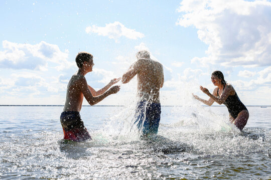 A family splashes water together in the sea during a sunny weekend