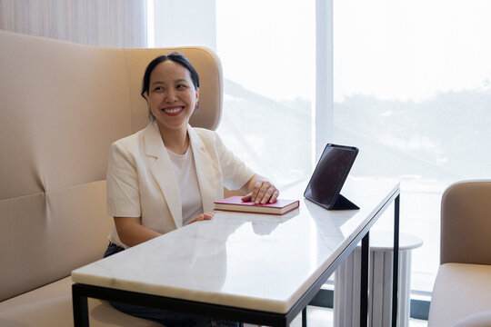 Smiling businesswoman sitting at marble table in modern lounge