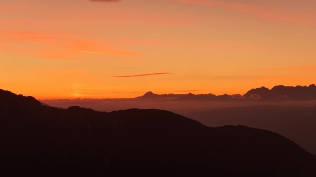 Dolomites mountain silhouettes glowing beneath an orange sunset