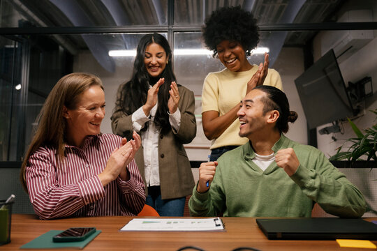 Team celebrates business success during meeting in office