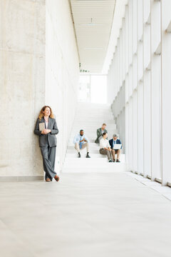 Confident businesswoman takes a break in modern office with team