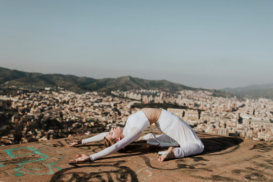 Woman practices a yoga backbend outdoors above Barcelona