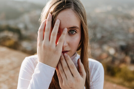 Girl covers her face with hands outdoors