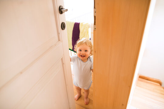 Portrait of happy baby boy opening the door