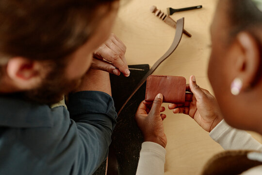 Man and woman crafting a handmade leather wallet in a workshop