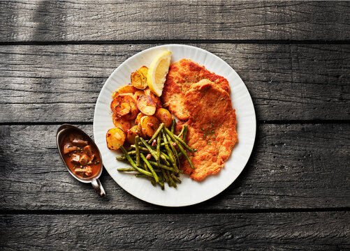 A plate features traditional German jaegerschnitzel with beans