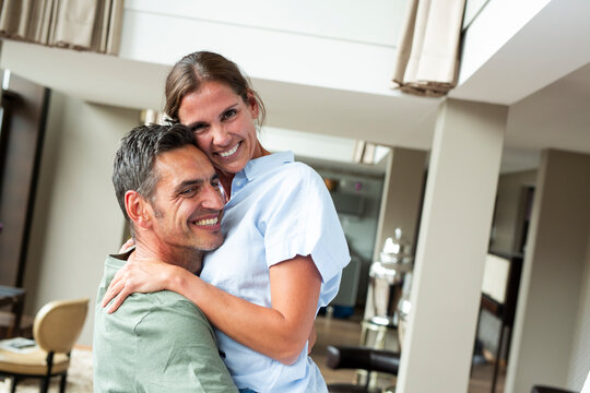 Smiling woman embraces man in modern home interior