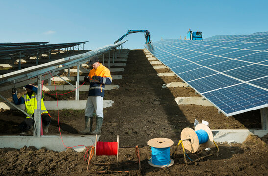 Workers installing solar panels at former landfill solarfarm outdoors