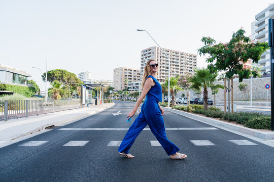 Smiling businesswoman walking across urban street in office district