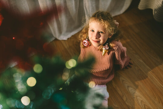 Playful girl wears a Christmas ornament as an earring